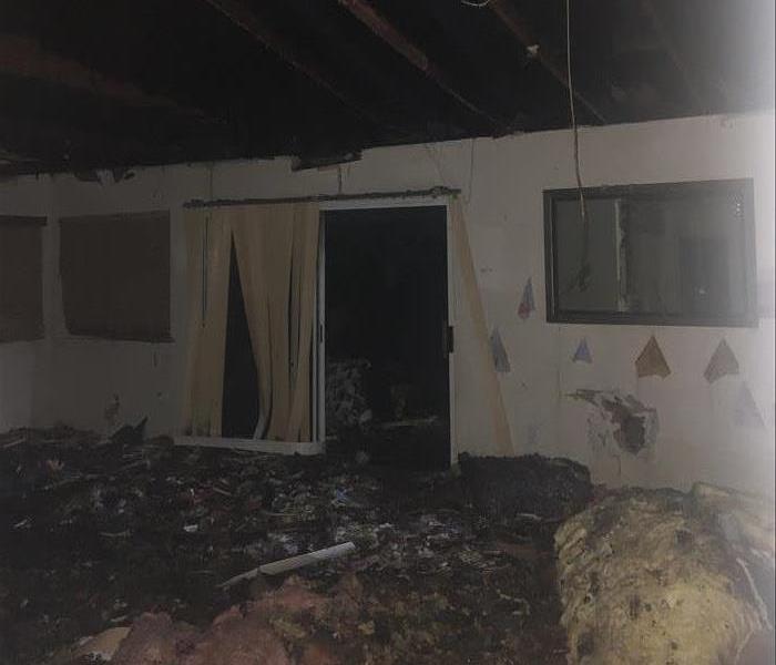 Fire damage causes extreme damage to roof, insulation, and walls of San Diego home living room or family room
